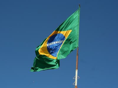 Brazilian flag on a pole waving, blue circle includes "ORDEM E PROGRESSO"