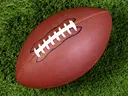 American football with white laces lying on green grass
