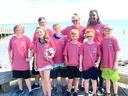 Nine children in pink camp shirts near water