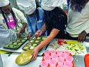 Group of youth in chef hats filling muffin tins with vegetable mixtures and sliced zucchini