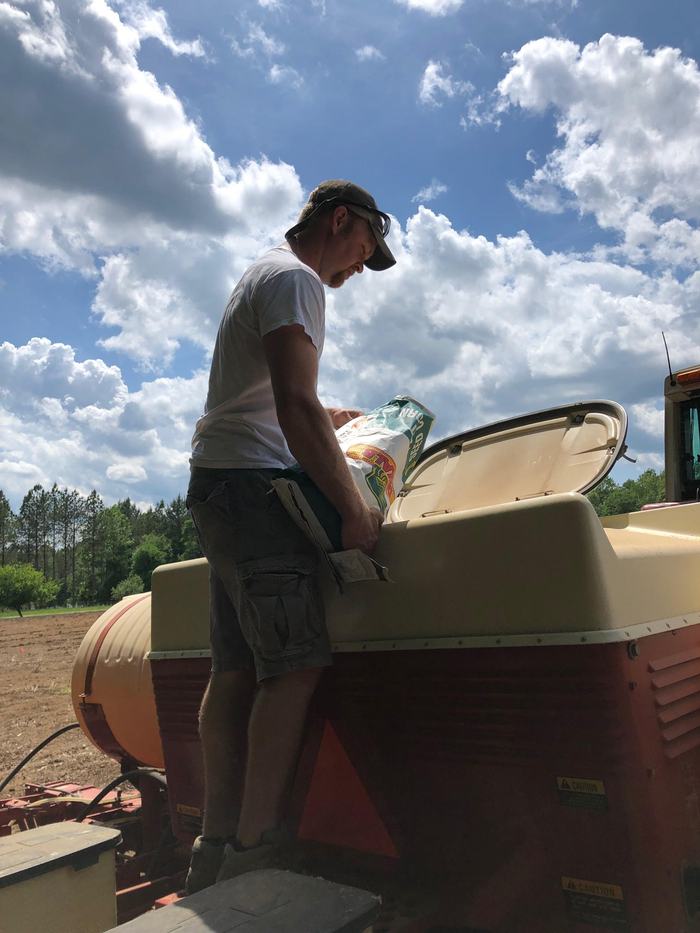 A man empties a bag into a hopper.