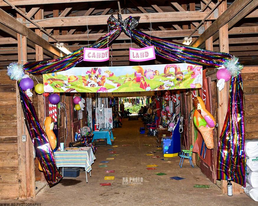 Barn aisle decorated as "CANDY" and "LAND" signs with colorful streamers and balloons