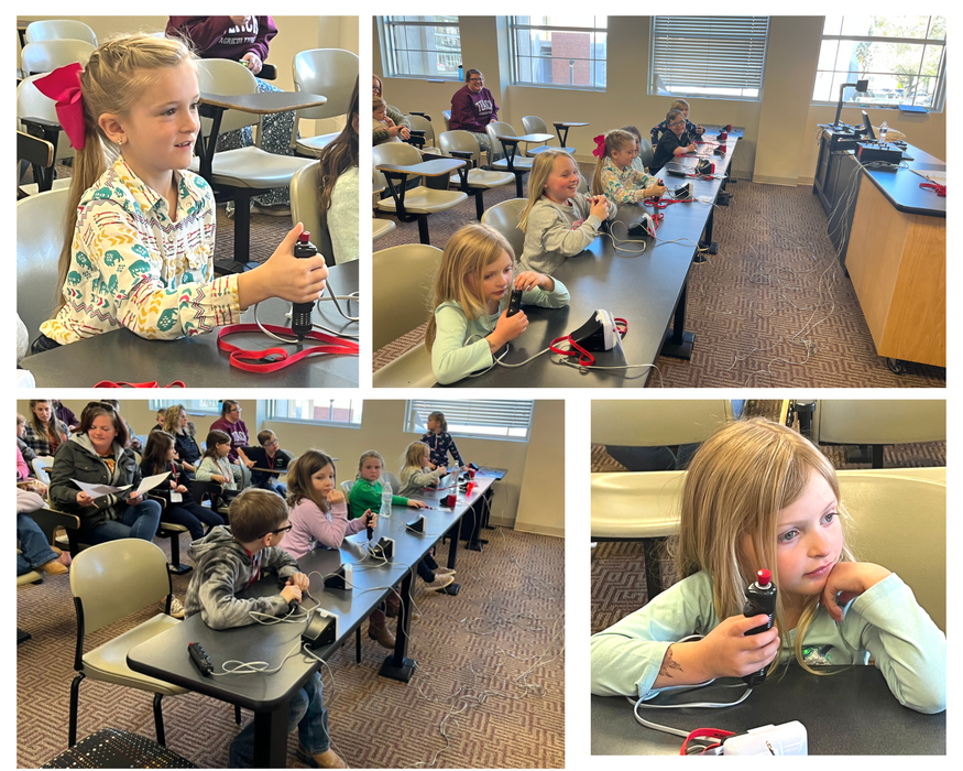 Children in classroom using handheld buzzers at desks during group activity