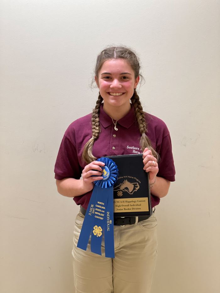 Person holding plaque and blue ribbon reading "North Carolina State 4‑H Hippology Contest, Junior Individual"