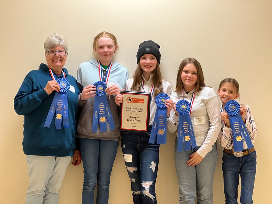 Five people holding blue ribbons and a plaque reading "Champion Junior Team (North Carolina 4‑H)"