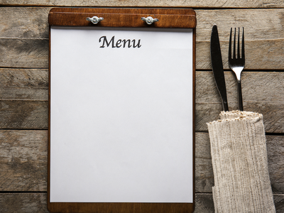 Blank menu board beside fork and knife wrapped in cloth napkin