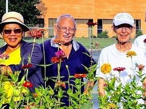 A group of volunteers stand among flowers.