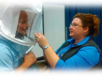 Individual wearing a protective hood while another person adjusts its zipper