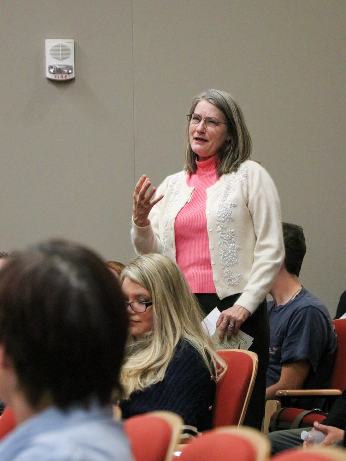 Woman standing and speaking to a seated audience in a meeting room