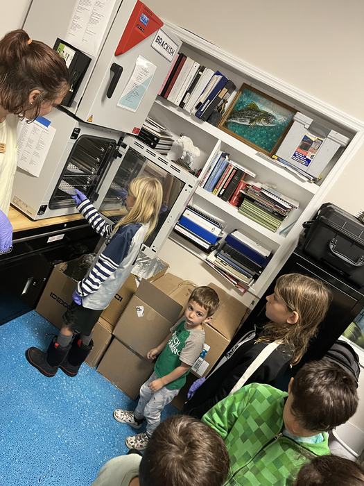 Students look inside lab equipment.