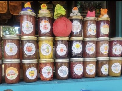 Rows of labeled jam jars on a shelf, several jars topped with small rubber duck toys