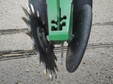 Fluted planter disc opener and adjacent rubber gauge wheel on green implement