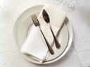 White dinner plate with folded napkin and a fork and knife placed on top