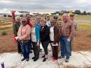 Twelve adults standing together outdoors near event tents and hay bales.