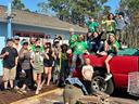 Group of children and adults posing by a red pickup truck, many giving thumbs up