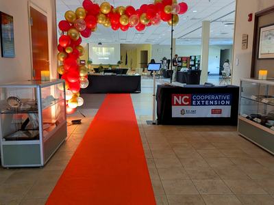 Red carpet going under a balloon arch leading to a refreshments table