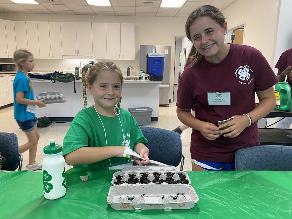 teen leader helping camper plant seeds at gARTen camp