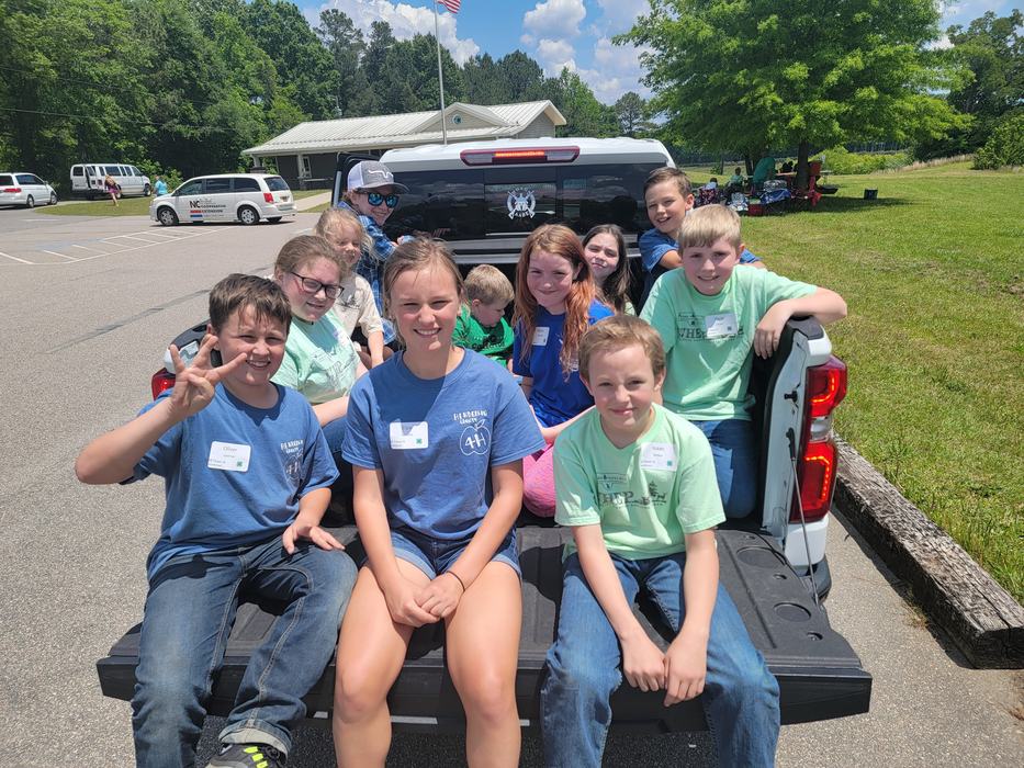A group of kids sitting in the back of a pickup truck.
