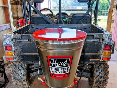 UTV rear with mounted Herd Sure-Feed Broadcaster labeled "Herd SURE-FEED BROADCASTER"