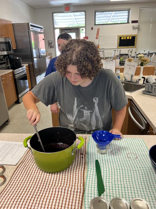 A teenager stirs a pot.