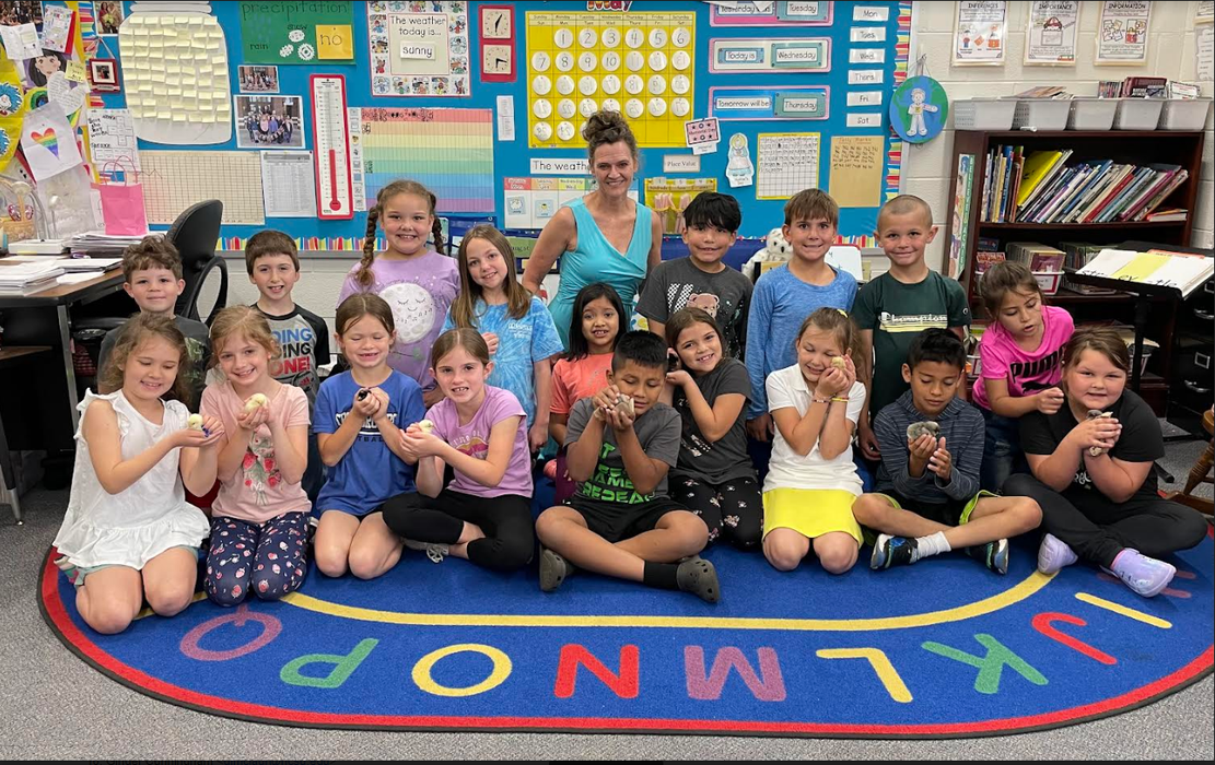 Elementary classroom teacher and students on alphabet rug holding baby chicks