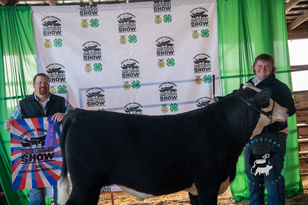 Two men holding Grand Champion Market Steer at Central Piedmont Junior Livestock Show