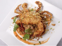 Fried soft-shell crab on white plate with sauce swirl, cilantro, and crispy crumbs