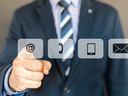 Person in suit pointing at @ icon among contact icons: phone, tablet, envelope