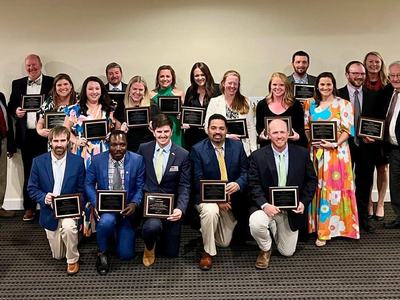 A group of graduates pose with plaques.