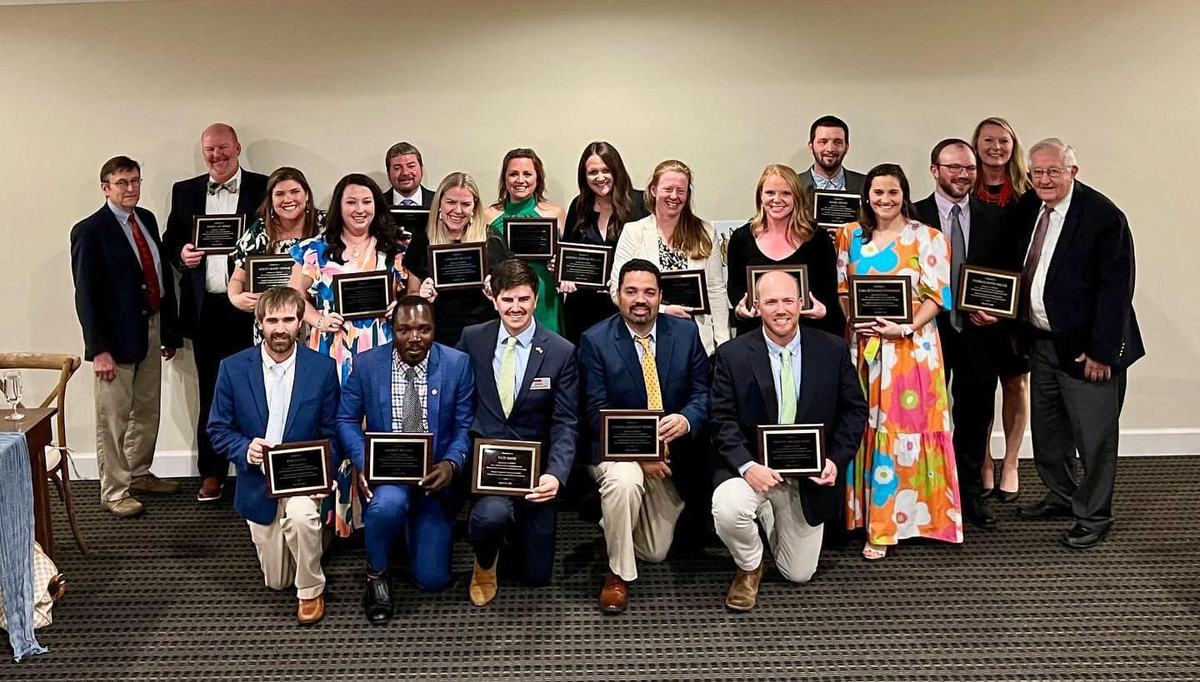 A group of graduates pose with plaques.