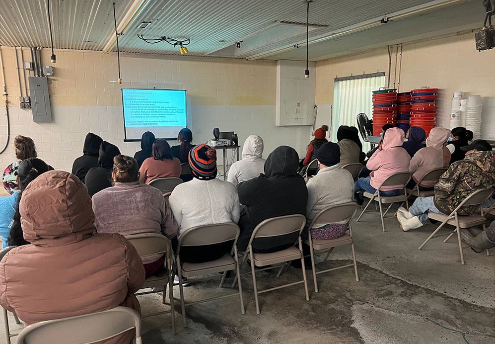 Photo of 20 seafood processing workers attend video training class.