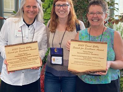 Three women display award plaques.