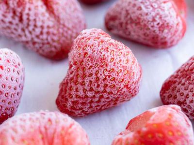 Frozen strawberries covered in frost crystals on a white surface