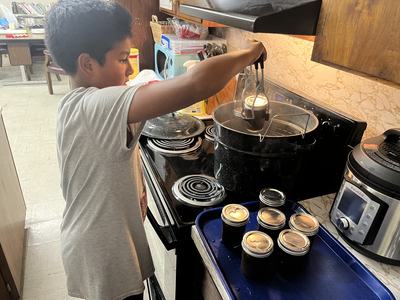 4-H youth removing completed apple butter from the hot water bath canner