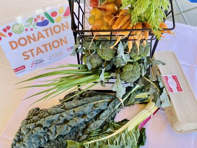 DONATION STATION sign; table with basket of vegetables (kale, broccoli, carrots, tomatoes) and egg carton