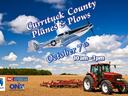 An airplane flying through the air and a tractor plowing a field