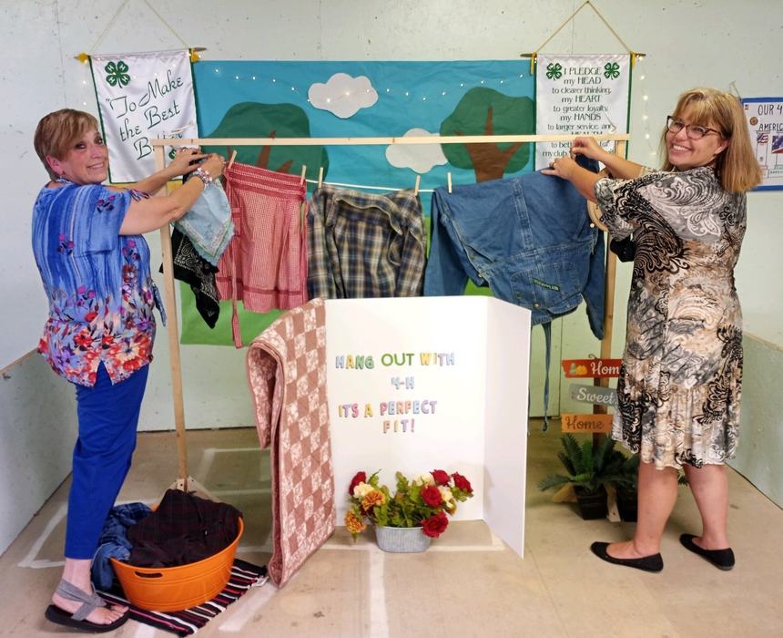 Volunteer leaders Janie Rickman, left, and Karla Ford, right, put the finishing touches on the Bear Paws 4-H Club's booth at the agricultural fair in Lenoir in 2021.