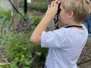 Student with binoculars in the Pollinator Haven Garden
