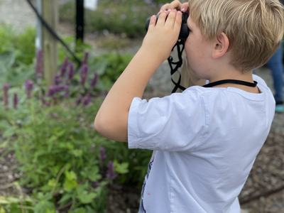 Student with binoculars in the Pollinator Haven Garden