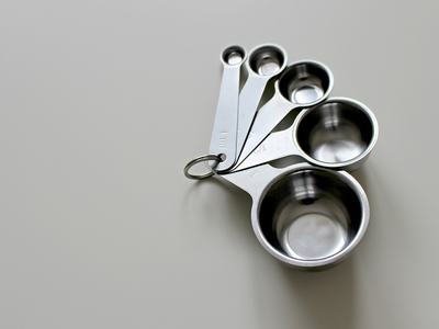 Set of five nested stainless steel measuring spoons on a light surface