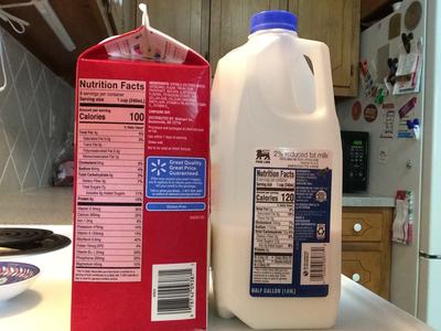 Red soy milk carton (Calories 100) beside 2% milk jug (Calories 120) on kitchen counter