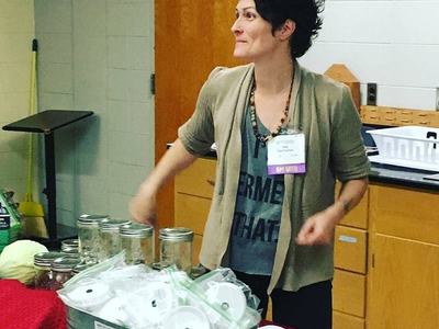 A woman shows off fermenting equipment.