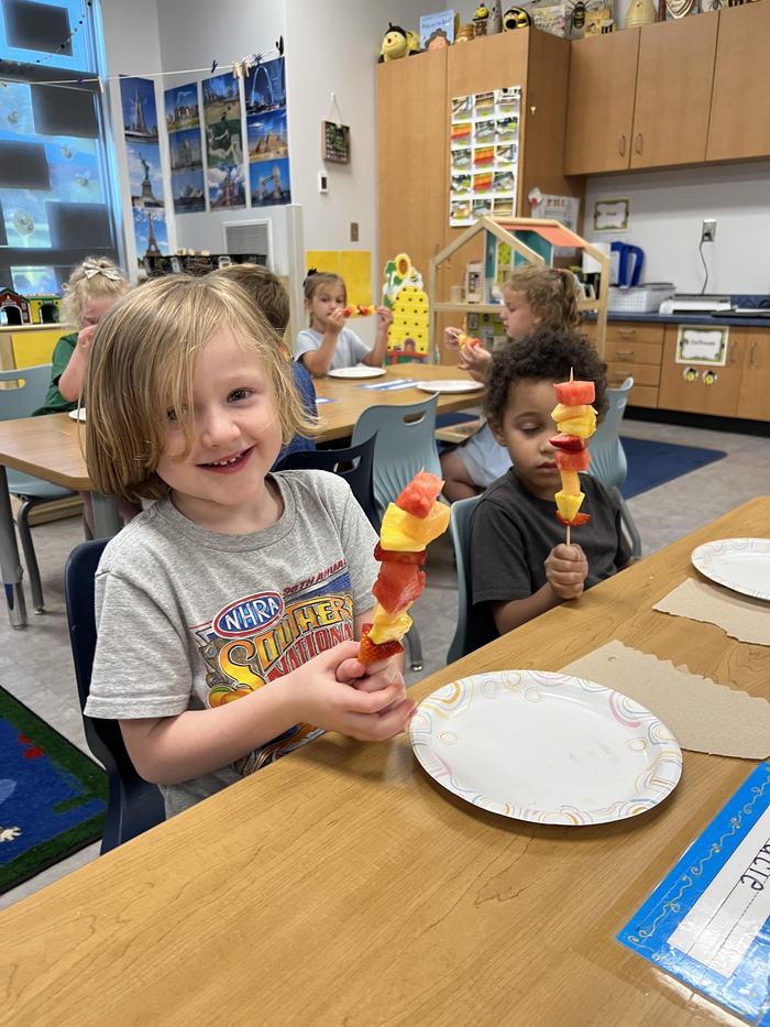 Two children hold their fruit skewers.