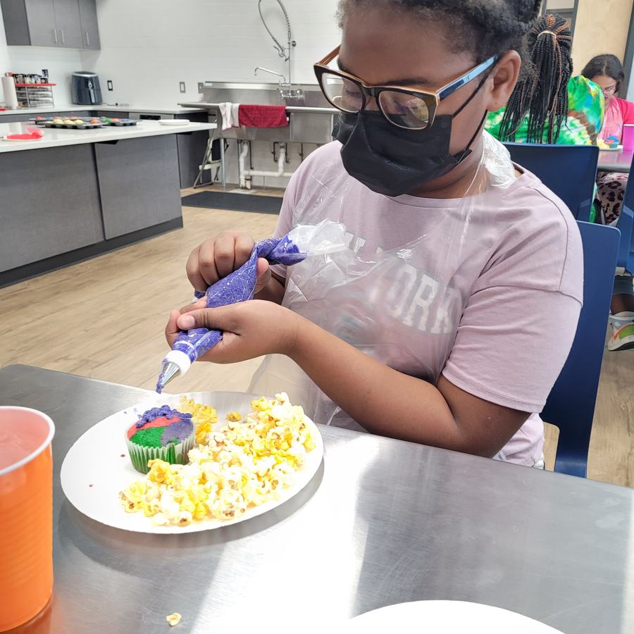 child applying icing to a cupcake