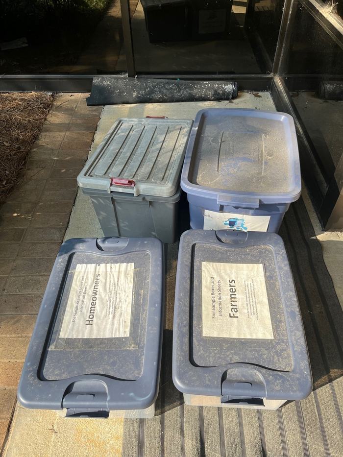 Four plastic storage bins on a doorstep, two lids labeled "Homeowners" and "Farmers"