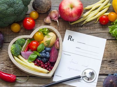 Heart-shaped bowl of produce beside Rx form reading "fruit and vegetables" with stethoscope