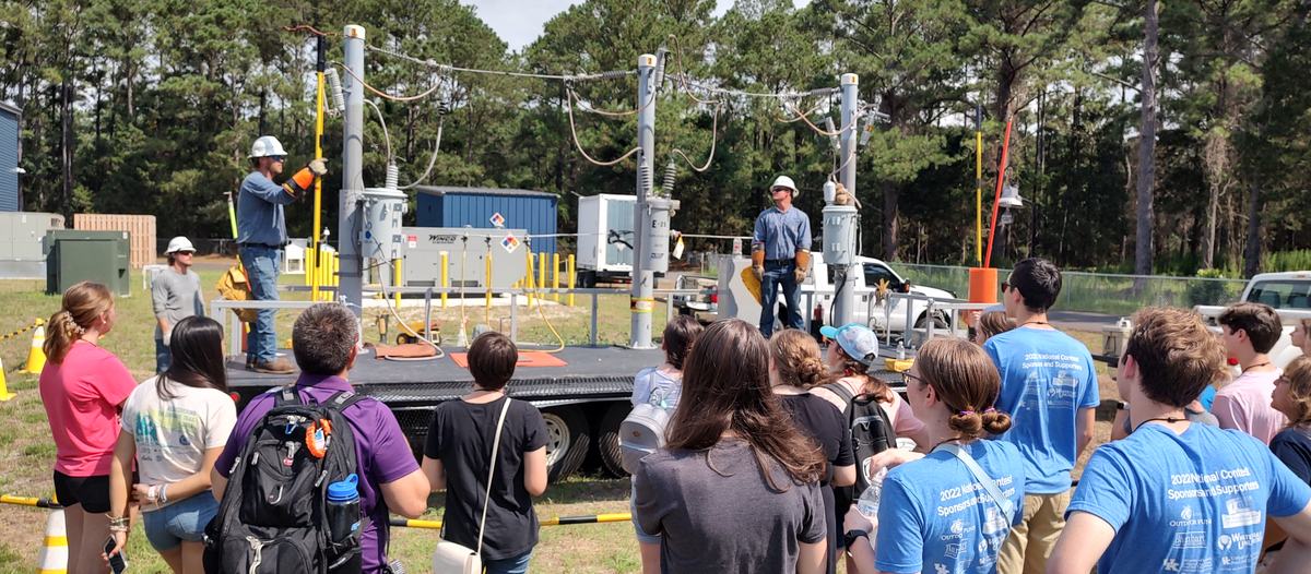 Kids watch a demonstration of line workers. 
