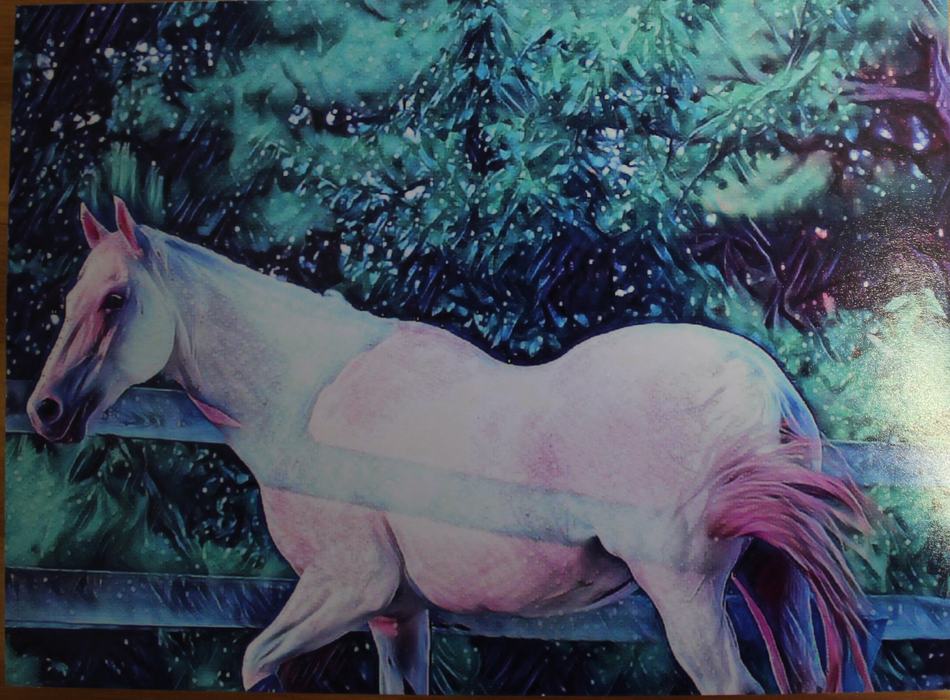 White horse standing beside a wooden fence in front of dense green foliage.