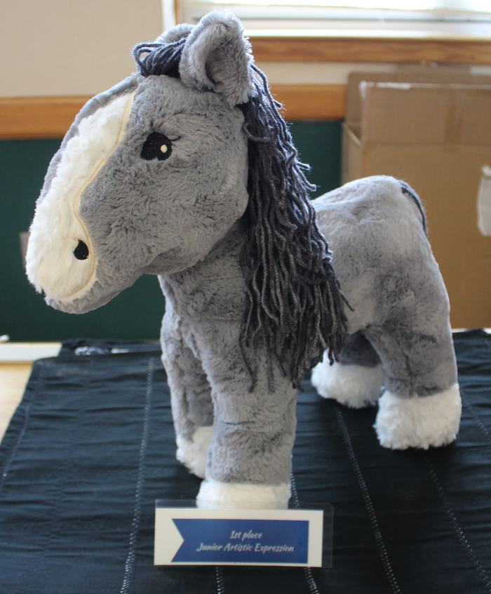 Gray stuffed horse with yarn mane on table; plaque: "1st place Junior Artistic Expression"