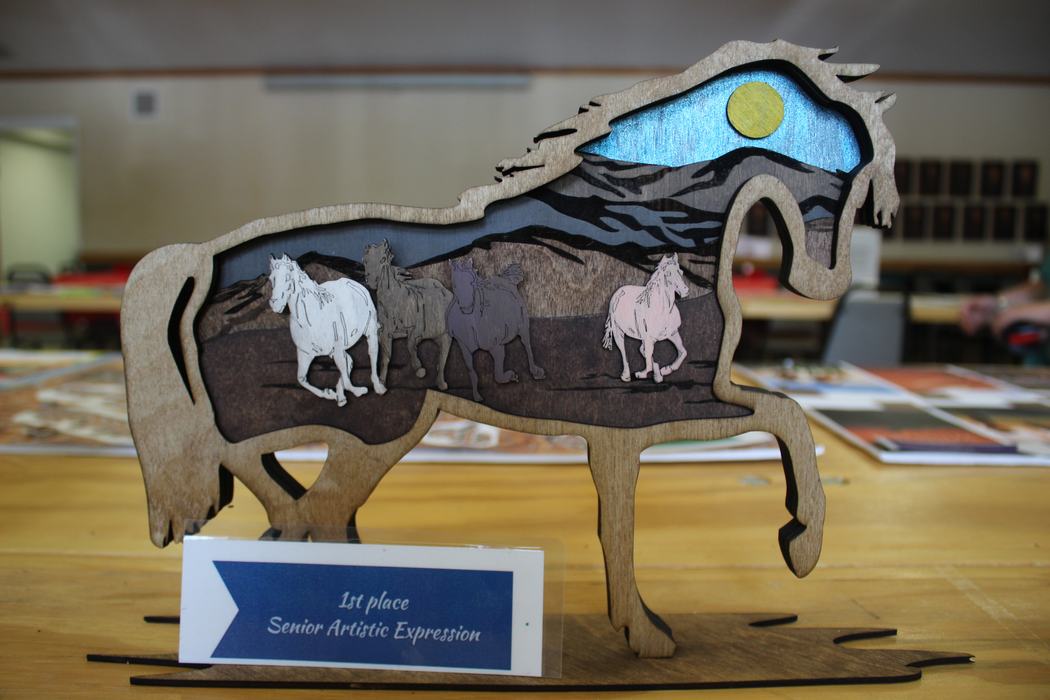 Wooden horse-shaped plaque with carved running horses; sign reads "1st place Senior Artistic Expression"